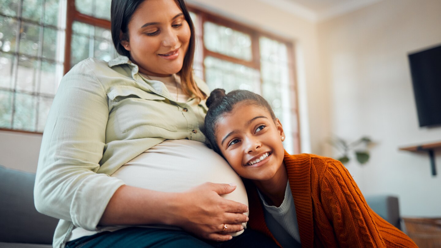 Kind hört Babybauch an
