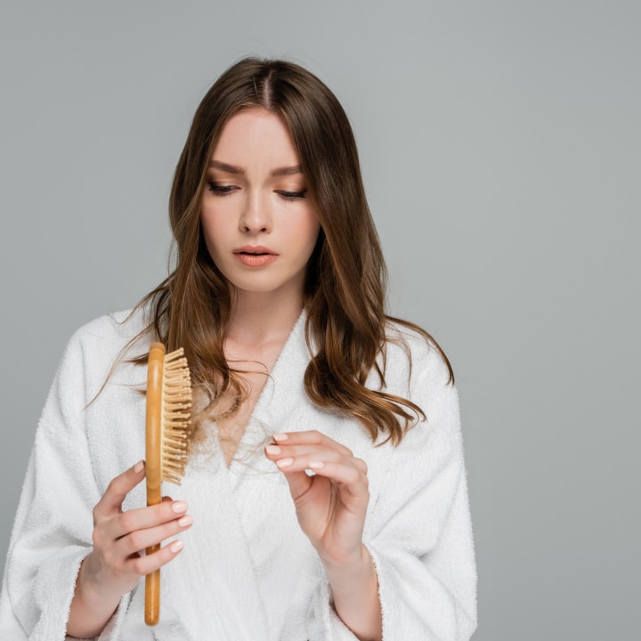 stressed young woman holding wooden hair brush